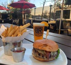 Burger, fries, and beer on table at outdoor sitting area