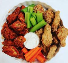 Plate of chicken wings with vegetables.