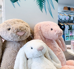 Three rabbit plushies displayed in front of wall