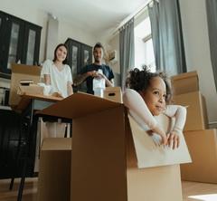 Child inside cardboard box with parents in the background