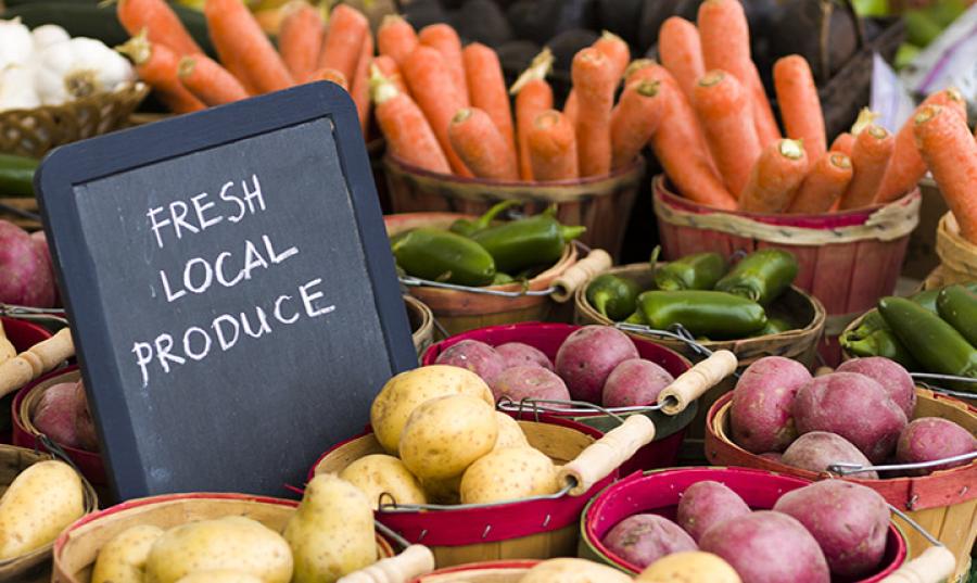Produce on display with a sign stating "FRESH LOCAL PRODUCE"