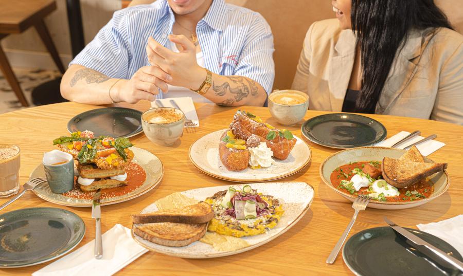 plates of food at a restaurant with two people in the background smiling